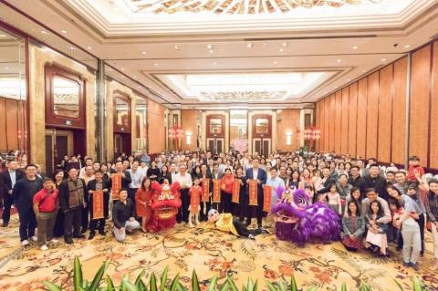 Large group of people with lion dancers in a banquet hall.